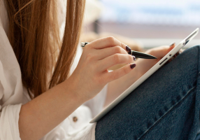 Porque comprar ou alugar com a nossa imobiliária? Agilidade e comodidade Mulher sentada escrevendo algo em seu tablet